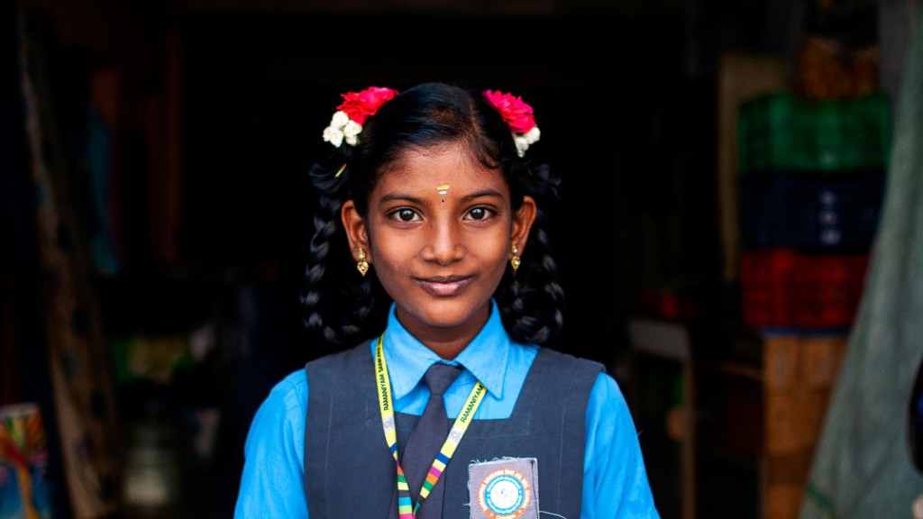 A schoolgirl in uniform with flowers in her hair smiling gently