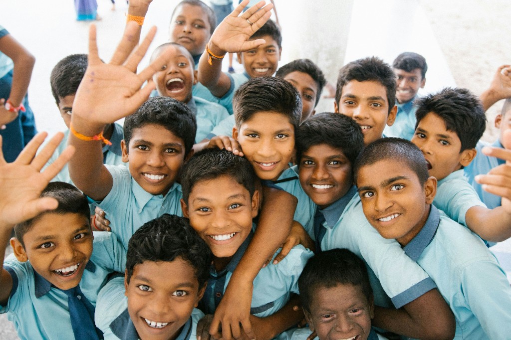 A group of joyful schoolboys in light blue uniforms huddling together and smiling at the camera